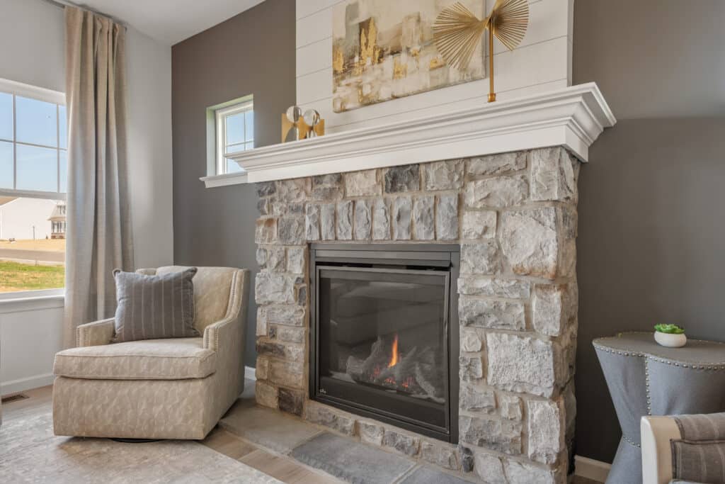 A cozy corner with a stone fireplace and a single armchair in a modern living room.