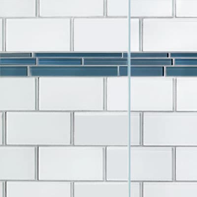 White subway tiles with a single vertical line of blue accent tiles adorn the shower, complemented by clear shower doors.