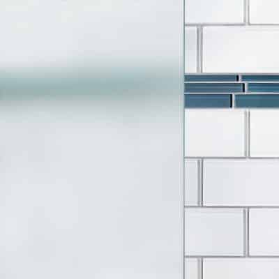 Frosted glass shower doors beside a white tiled wall with one row of blue accent tiles.