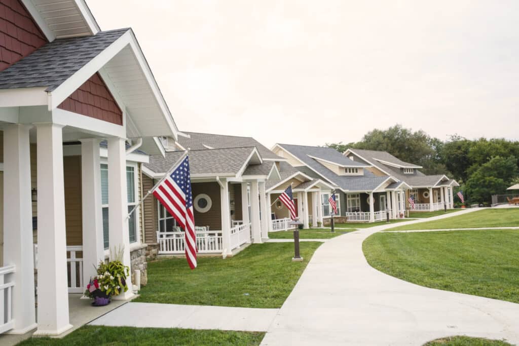 A row of suburban houses with American flags displayed on their porches presents a quintessential commercial representation of patriotic suburbia.